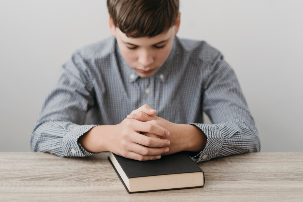 imagem ilustrativa cristianismo menino orando com Bíblia